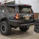 A lifted black Toyota 4Runner SUV with large off-road tires, shown from a rear three-quarter angle inside a garage.